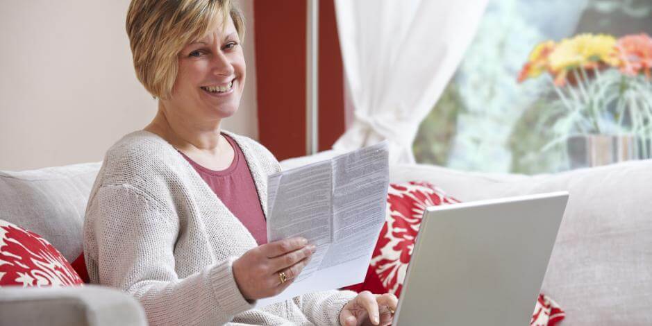 Woman holding papers in front of computer